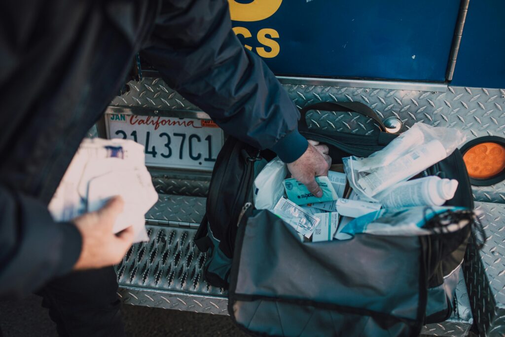 A first responder accessing medical supplies from a bag beside an emergency vehicle.